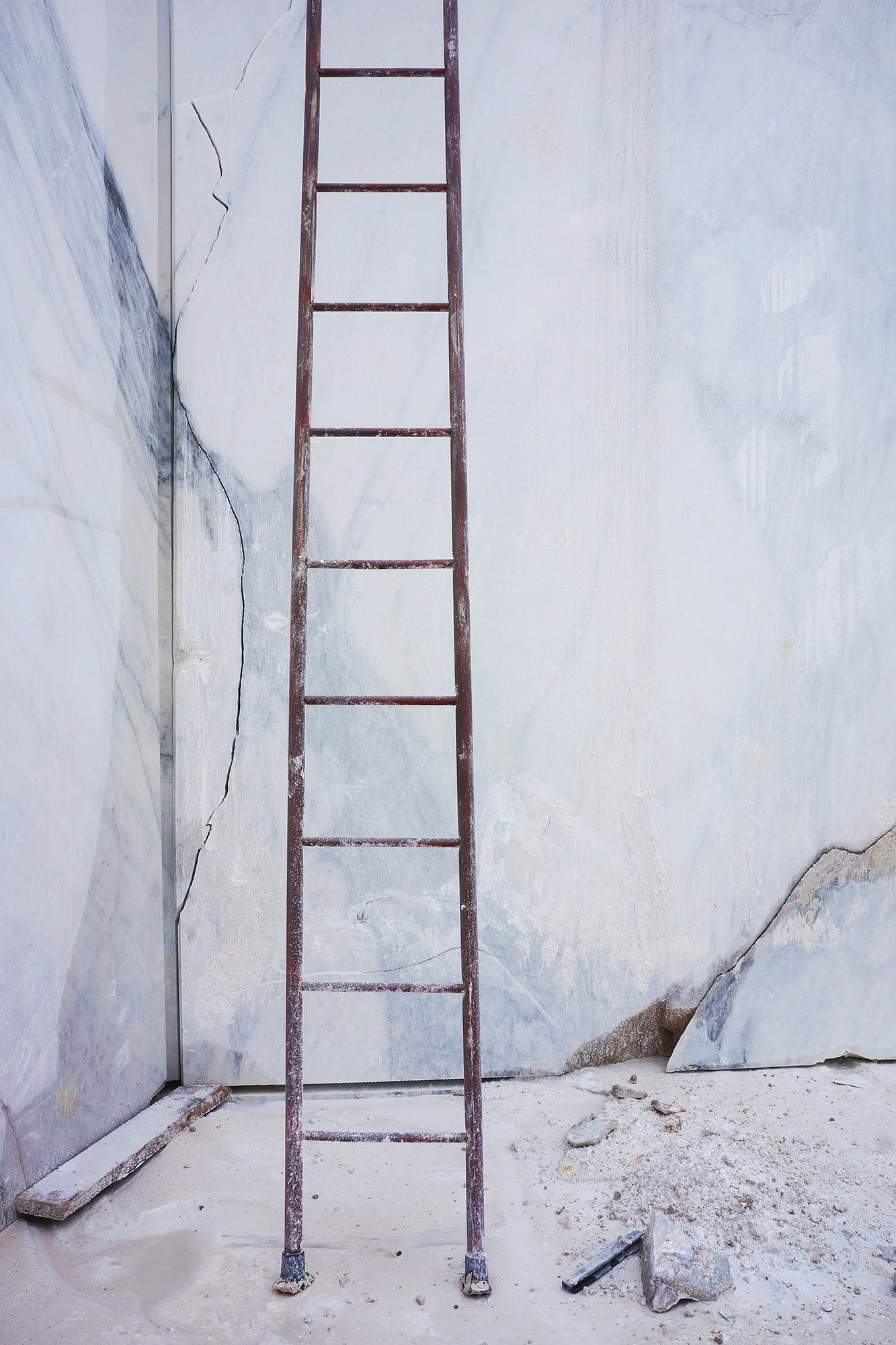 A ladder in front of cracked marble walls.